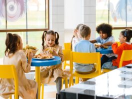 Group of children eating together at a school cafeteria, sharing joy and food.