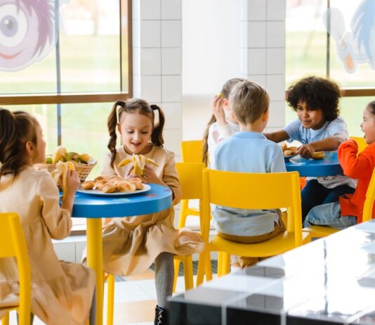 Group of children eating together at a school cafeteria, sharing joy and food.