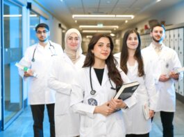 Group of diverse medical students wearing lab coats in university corridor, representing future healthcare professionals.