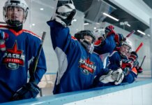 Group of ice hockey players in blue jerseys celebrating a win indoors.