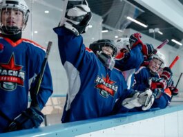 Group of ice hockey players in blue jerseys celebrating a win indoors.