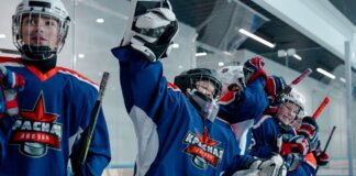 Group of ice hockey players in blue jerseys celebrating a win indoors.