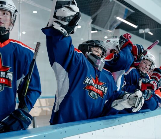 Group of ice hockey players in blue jerseys celebrating a win indoors.