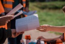 Group of volunteers handing out missing person flyers during a search operation outdoors.