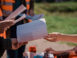 Group of volunteers handing out missing person flyers during a search operation outdoors.