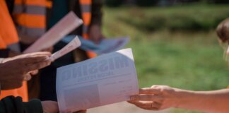 Group of volunteers handing out missing person flyers during a search operation outdoors.