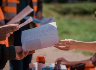 Group of volunteers handing out missing person flyers during a search operation outdoors.