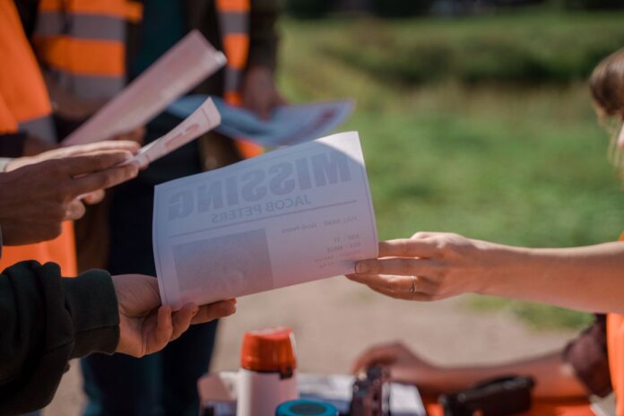 Group of volunteers handing out missing person flyers during a search operation outdoors. Group of volunteers handing out missing person flyers during a search operation outdoors.
