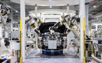Оттава инвестирует в Prevost в Квебеке: завод Volvo переходит на электрические автобусы High-tech robots assembling a car in a modern factory setting, showcasing automation.