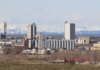Industrial area in Calgary with Rocky Mountains backdrop, showcasing urban development.