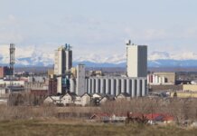 Industrial area in Calgary with Rocky Mountains backdrop, showcasing urban development.