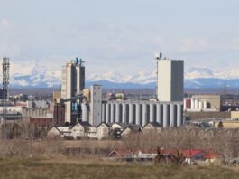 Industrial area in Calgary with Rocky Mountains backdrop, showcasing urban development.