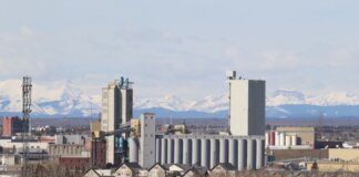 Industrial area in Calgary with Rocky Mountains backdrop, showcasing urban development.