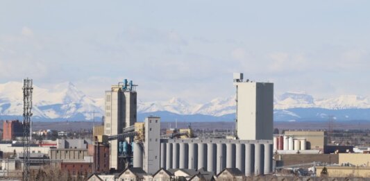 Industrial area in Calgary with Rocky Mountains backdrop, showcasing urban development.