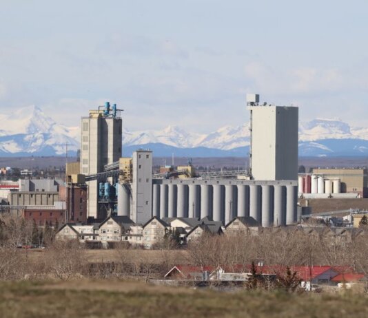 Industrial area in Calgary with Rocky Mountains backdrop, showcasing urban development.