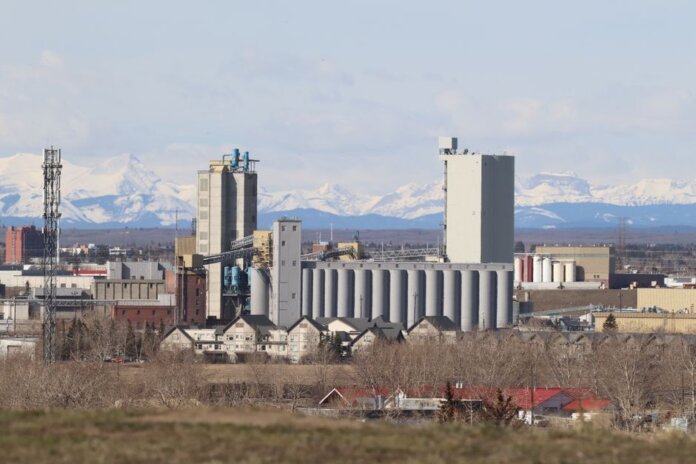 Industrial area in Calgary with Rocky Mountains backdrop, showcasing urban development. Industrial area in Calgary with Rocky Mountains backdrop, showcasing urban development.