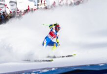 Intense ski race action captured with athlete carving through snowy slope in winter.