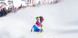 Intense ski race action captured with athlete carving through snowy slope in winter.