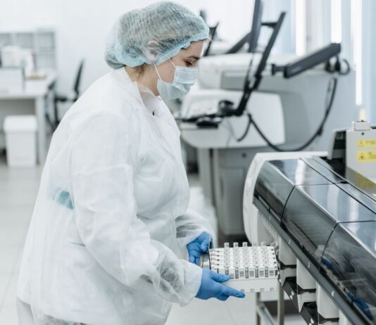Laboratory scientist in protective gear working with medical samples.