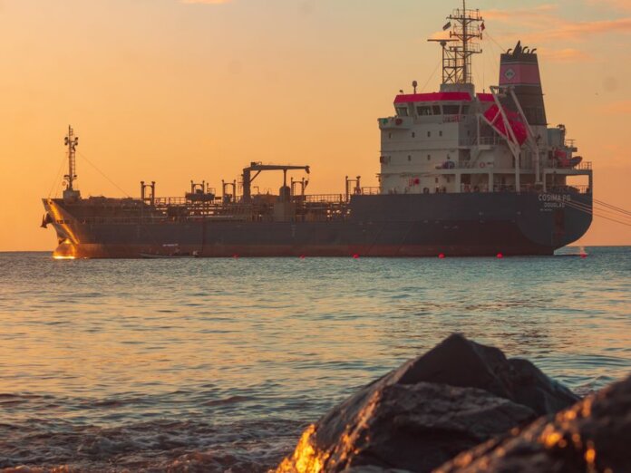 Large oil tanker on the ocean near the coast, sailing under a vibrant sunset sky. Large oil tanker on the ocean near the coast, sailing under a vibrant sunset sky.