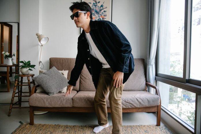 Man with sunglasses and cane navigating modern living room, embodying independence. Man with sunglasses and cane navigating modern living room, embodying independence.