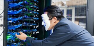 Masked individual interacting with server racks, symbolizing cybersecurity threats.