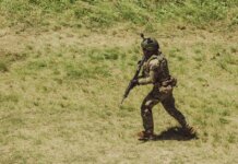 Military soldier in tactical gear running during training exercise at Campo de Mayo, Argentina.