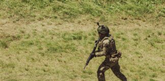 Military soldier in tactical gear running during training exercise at Campo de Mayo, Argentina.