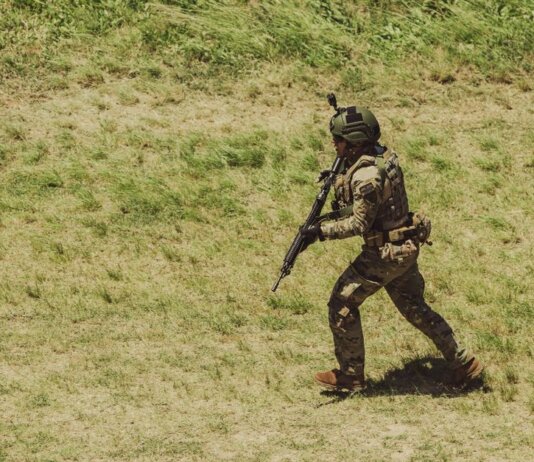 Military soldier in tactical gear running during training exercise at Campo de Mayo, Argentina.