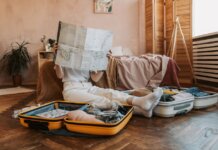 Person packing suitcases with a map in a cozy bedroom, preparing for a journey.