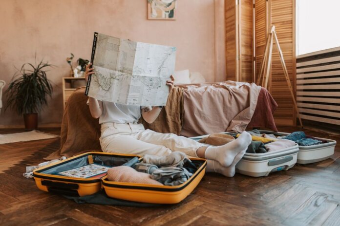 Person packing suitcases with a map in a cozy bedroom, preparing for a journey. Person packing suitcases with a map in a cozy bedroom, preparing for a journey.