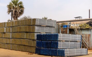 Консерваторы обвинили правительство Карни в отказе от принципа «покупай канадское» Piles of stacked metal beams in an industrial outdoor yard under a clear sky.