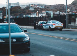 Police car parked on asphalt road near modern vehicles in city district in evening