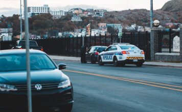 Police car parked on asphalt road near modern vehicles in city district in evening