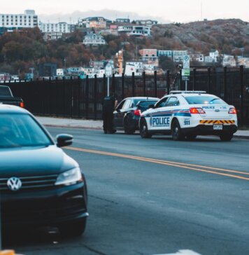Police car parked on asphalt road near modern vehicles in city district in evening