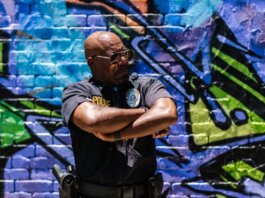 Police officer standing confidently against colorful urban graffiti wall.