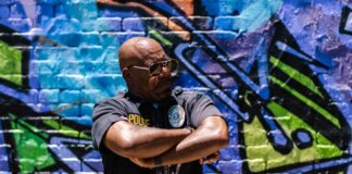 Police officer standing confidently against colorful urban graffiti wall.