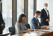 Professionals in face masks having a business meeting in a modern conference room.