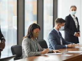 Professionals in face masks having a business meeting in a modern conference room.