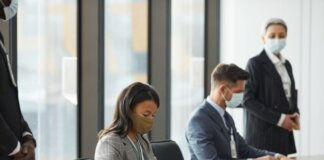 Professionals in face masks having a business meeting in a modern conference room.
