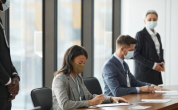 Professionals in face masks having a business meeting in a modern conference room.