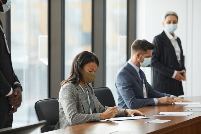 Professionals in face masks having a business meeting in a modern conference room. Professionals in face masks having a business meeting in a modern conference room.