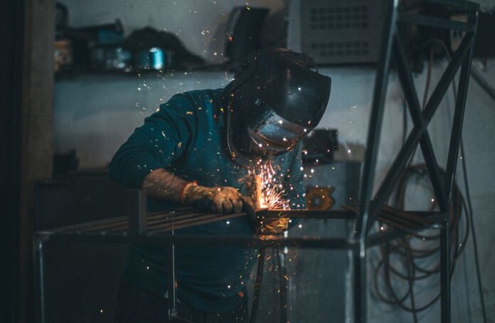 Skilled welder works with sparks in an industrial workshop setting, wearing safety gear. Skilled welder works with sparks in an industrial workshop setting, wearing safety gear.