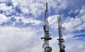 Оттава представила первую Дорожную карту по конкуренции в телекоммуникациях Telecommunication towers with antennas and dishes under a bright cloudy sky.
