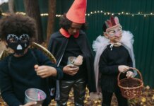 Three children in creative Halloween costumes collect candy outdoors during trick-or-treat.