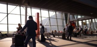 Travelers in a bustling airport terminal with carry-on luggage waiting for departure.