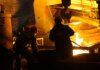 Консерваторы представили план защиты рабочих канадской сталелитейной отрасли Two workers operate in a steel factory, managing molten metal in an industrial furnace.