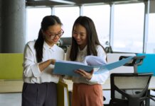 Two young women engaged in a collaborative discussion in a bright, modern office setting.