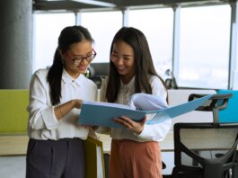 Two young women engaged in a collaborative discussion in a bright, modern office setting.