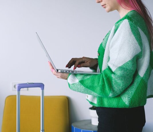 Young woman working on laptop near luggage in stylish hotel lounge, embracing the digital nomad lifestyle.